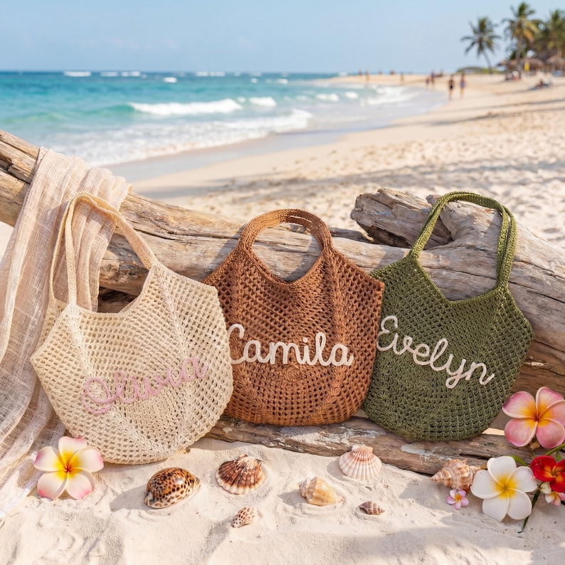 May include: Three crocheted tote bags in beige, brown, and olive green, each with a name embroidered in a contrasting color: "Chloe", "Camila", and "Evelyn". The bags are displayed on a sandy beach with seashells and flowers.