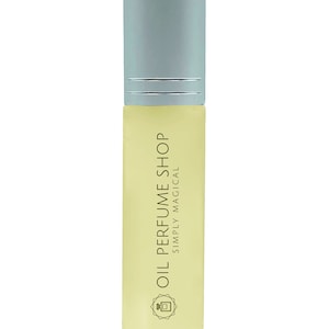 May include: A clear glass bottle with a silver cap and a yellow label that reads "Oil Perfume Shop Simply Magical". The bottle has a small, stylized image of a perfume bottle on the label.
