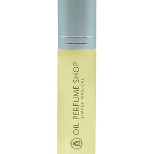 K&ouml;nnte beinhalten: Eine klare Glasflasche mit einem silbernen Verschluss und einem gelben Etikett mit der Aufschrift "Oil Perfume Shop Simply Magical". Die Flasche hat ein kleines, stilisiertes Bild eines Parf&uuml;mflakons auf dem Etikett.