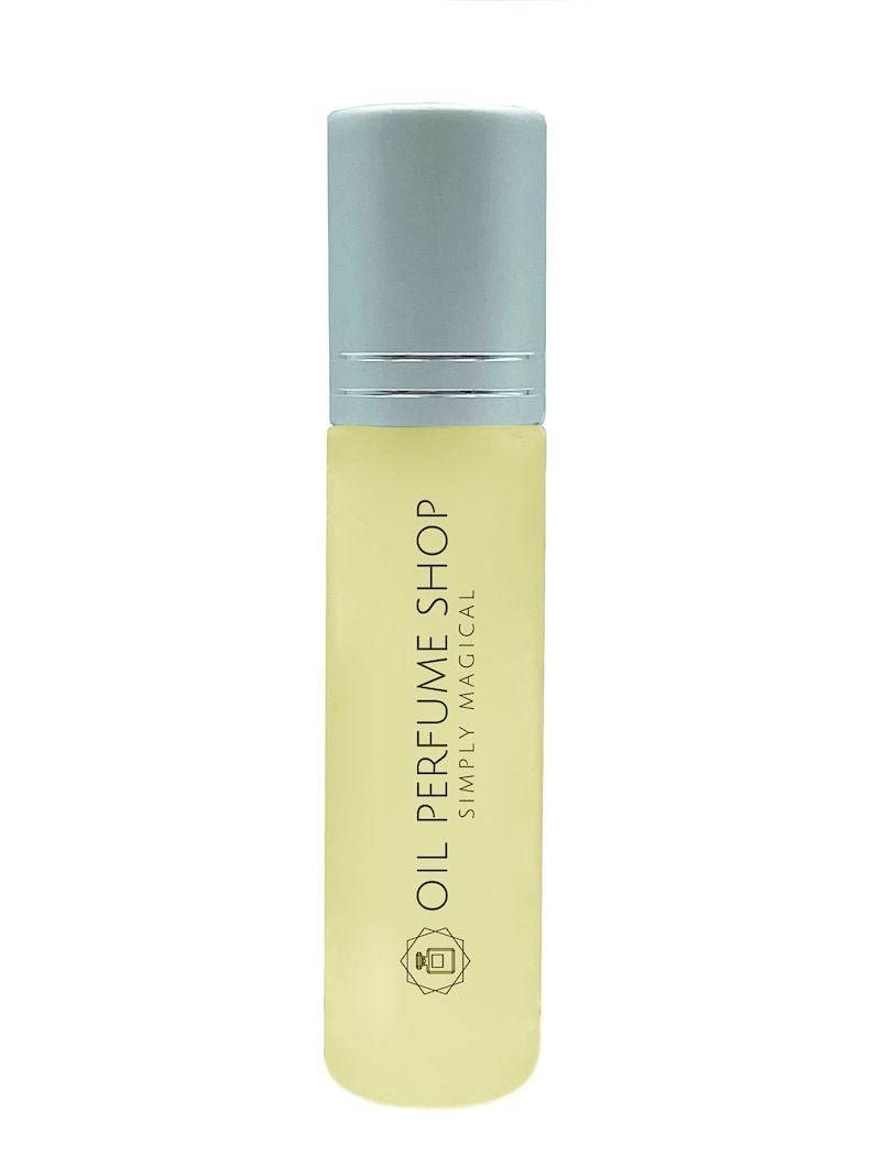 K&ouml;nnte beinhalten: Eine klare Glasflasche mit einem silbernen Verschluss und einem gelben Etikett mit der Aufschrift "Oil Perfume Shop Simply Magical". Die Flasche hat ein kleines, stilisiertes Bild eines Parf&uuml;mflakons auf dem Etikett.