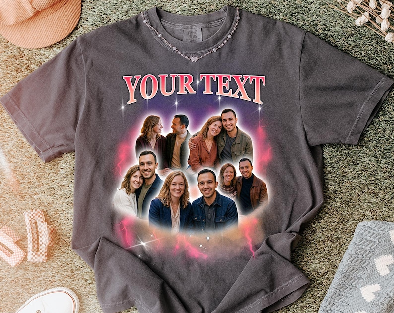 May include: Dark gray t-shirt with the text "YOUR TEXT" in pink and white. The shirt features a graphic of several couples in a circular design. A silver necklace with butterfly accents is visible.