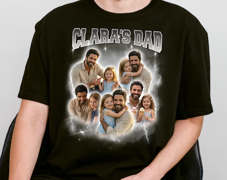 May include: Black t-shirt with the text "CLARA'S DAD" in white and gray. The shirt features a collage of photos of a man and two young girls, surrounded by a cloudy, lightning-bolt design.
