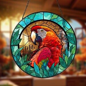 May include: A round stained glass window featuring a vibrant macaw parrot design. The parrot has red, orange, and yellow feathers, with a white beak and a green eye. The name "Milo" is written on the glass. The window is framed with green leaves and a blue border.