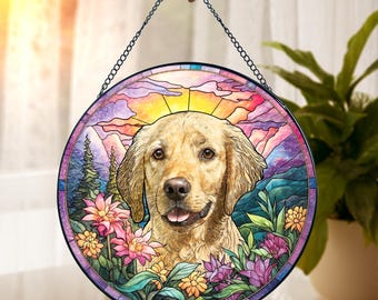 May include: Round stained glass window art featuring a golden retriever dog with a colorful sunset and mountain scene. The dog is surrounded by flowers in shades of pink, purple, and yellow. A black chain is attached for hanging.