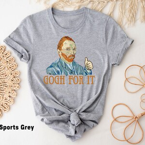 May include: A gray t-shirt with a graphic of Vincent van Gogh giving a thumbs up and the text "GOGH FOR IT".