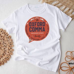 May include: White t-shirt with a red circle graphic that says "The Oxford Comma" with the text "Defenders of Tradition, Form, and Clarity" around the circle.