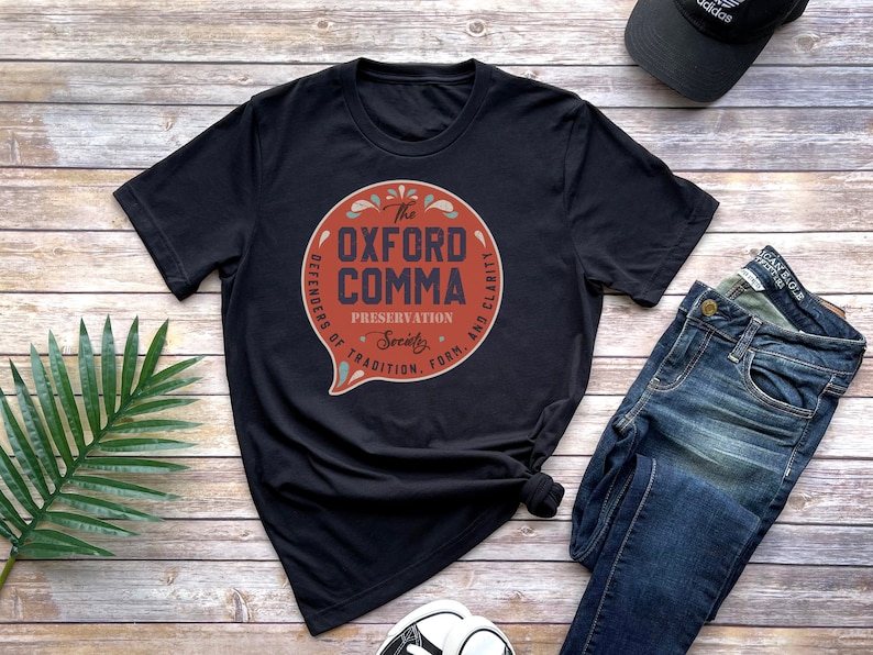 May include: Black t-shirt with a red circle graphic that says "The Oxford Comma" with the text "Defenders of Tradition, Form, and Clarity" around the circle.