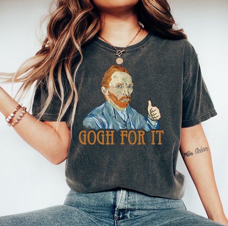 May include: A dark gray t-shirt with a graphic of Vincent van Gogh giving a thumbs up and the text "GOGH FOR IT".