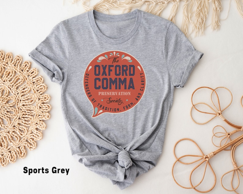 May include: A heather grey t-shirt with a red circle graphic that says "The Oxford Comma Preservation Society. Defenders of Tradition, Form, and Clarity."