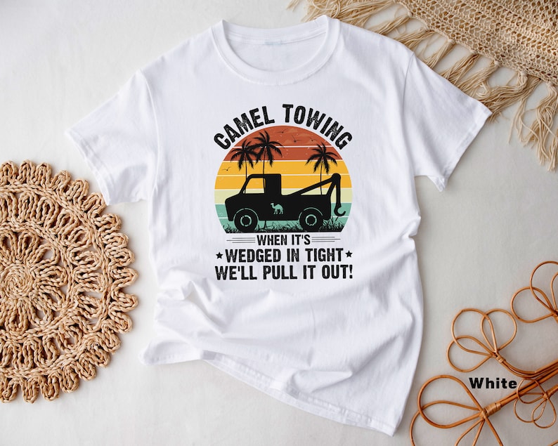 May include: White t-shirt with a vintage-style graphic of a camel towing a car. The graphic includes the text "Camel Towing" and "When it's wedged in tight, we'll pull it out!"