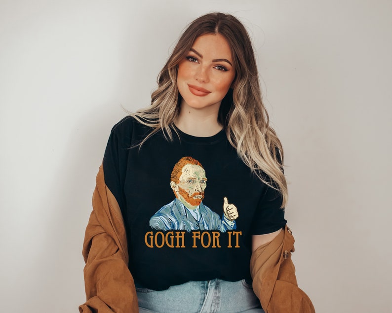 May include: A black t-shirt with a graphic of Vincent van Gogh giving a thumbs up. The text "Gogh for it" is printed below the graphic.