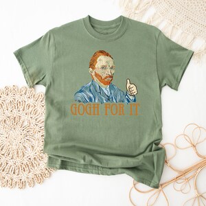 May include: Green t-shirt with a painting of Vincent Van Gogh giving a thumbs up. The text "GOGH FOR IT" is printed below the image.