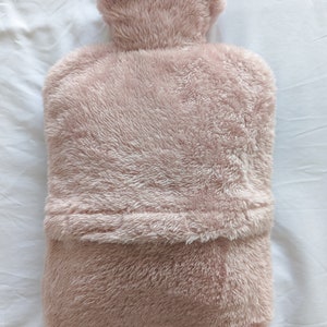 Op de afbeelding: Een pluche roze kruik met een zachte, donzige textuur. De kruik heeft een afgeronde bovenkant en een platte bodem.
