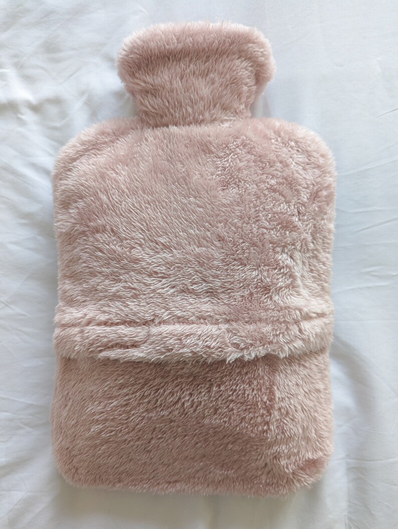 Op de afbeelding: Een pluche roze kruik met een zachte, donzige textuur. De kruik heeft een afgeronde bovenkant en een platte bodem.