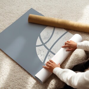 May include: A grey poster featuring a white basketball graphic, with a rolled-up poster and a brown cardboard tube. The image is taken from an elevated angle.