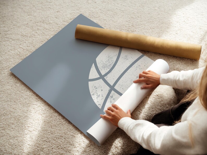 May include: A grey poster featuring a white basketball graphic, with a rolled-up poster and a brown cardboard tube. The image is taken from an elevated angle.