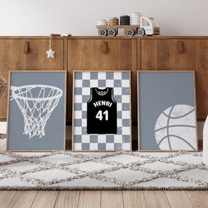 May include: Three framed prints with a basketball theme. One shows a white basketball net on a blue background. Another features a black jersey with "HENRI 41" on a checkered background. The third print displays a white basketball on a blue background.