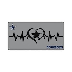 May include: A gray rectangle with a black heart and a star inside. The heart is surrounded by a black heartbeat line. The text "COWBOYS" is in blue at the bottom of the rectangle. A blue star is in the top left corner.