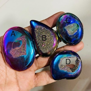 Puede incluir: Cuatro geodas pulidas e iridiscentes en tonos azules, morados y dorados. Cada geoda tiene una forma única y un centro de cristal brillante. Las geodas están etiquetadas A, B, C y D.
