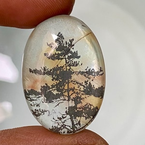 May include: A white ceramic mug with a black handle and the text "But First, Coffee" in a black, handwritten-style font. The mug is on a white surface.