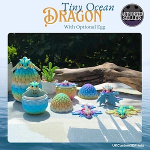 May include: A collection of colorful 3D-printed dragon figurines and egg-shaped containers. The dragons and eggs are in shades of blue, green, pink, and yellow. The text "Tiny Ocean Dragon" is displayed at the top of the image.