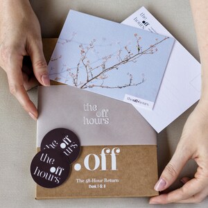 Könnte beinhalten: Ein brauner Pappkarton mit der Aufschrift .off The 48-Hour Return Book I & II, zwei dunklen runden Aufklebern mit der Aufschrift the off hours, einer hellblauen Postkarte mit einem Ast und einer weißen Karte mit dem Text the off hours.