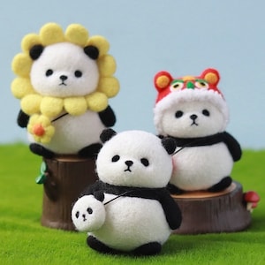 Może przedstawiać: Trzy urocze filcowe misie panda, każda z unikalnym dodatkiem. Jeden panda nosi żółty słonecznik, drugi nosi czerwony kapelusz tańca lwa, a trzeci nosi małego pandę.