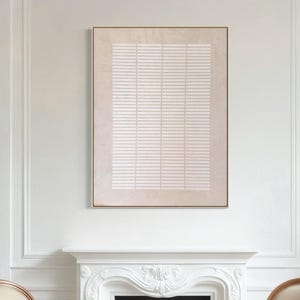May include: A dining room scene featuring a white round table and four chairs with beige upholstery and wooden frames. A framed abstract artwork with a beige background and white horizontal lines hangs above a white fireplace. The room has white walls and hardwood floors.