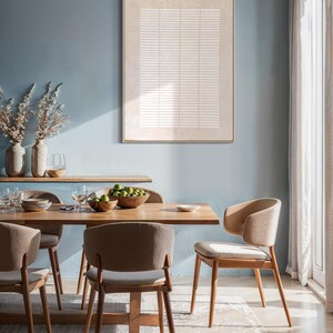 May include: A dining room scene featuring a light wood dining table and chairs. The chairs have curved backs and light-colored upholstery. A framed abstract artwork hangs on the blue wall. A wooden shelf holds vases and glassware. A bowl of limes sits on the table.