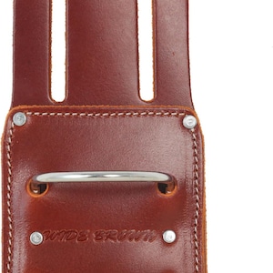 May include: A brown leather tool holder with a silver metal ring and the text "WIDE BROWN". The holder has two vertical slots and is stitched with white thread. Rivets secure the construction.