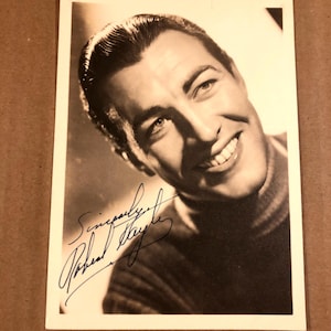 以下が含まれることがあります： 「敬具、ロバート・テイラー」という署名のある男性の白黒写真です。