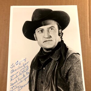 Könnte beinhalten: Schwarzweißfoto eines Mannes mit Cowboyhut und Weste. Der Mann blickt mit ernster Miene in die Kamera. Das Foto ist signiert mit "To Lynn, Thanks for your very kind letter. Good luck to you and your family. Tom."