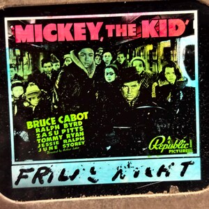 May include: A vintage movie poster for the film "Mickey, The Kid" featuring a group of actors in a scene from the film. The poster is in black and white with a green and yellow color scheme. The text on the poster reads "Mickey, The Kid" and "Bruce Cabot, Ralph Byrd, Zasu Pitts, Tommy Ryan, Jessie Ralph, June Storey". The poster also includes the text "Republic Pictures".
