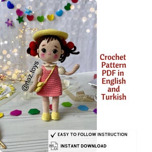 Op de afbeelding: Haakpatroon PDF in het Engels en Turks voor een gehaakte pop met een roze jurk, een gele hoed en bruin haar. De pop houdt een kleine gehaakte tas vast. De afbeelding bevat de tekst "@naz.toys", "Crochet Pattern PDF in English and Turkish", "EASY TO FOLLOW INSTRUCTION" en "INSTANT DOWNLOAD".