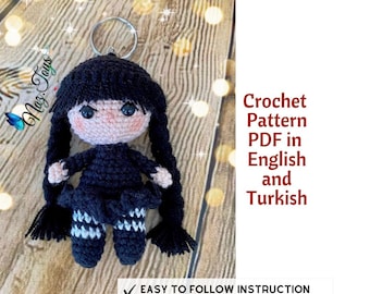 May include: Crochet pattern PDF in English and Turkish for a black and white amigurumi doll with pigtails. The doll is wearing a black dress and white and gray striped stockings. The pattern includes easy to follow instructions and is available for instant download.