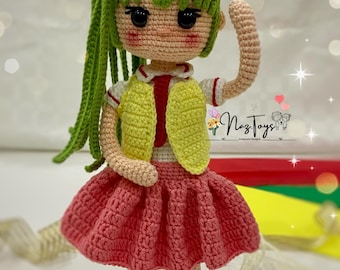 May include: A crocheted doll with green hair, a yellow vest, a pink skirt, and brown boots. The doll is standing on a white surface.