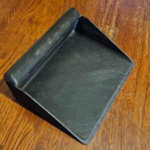 May include: A black plastic dustpan with a wooden handle. The dustpan is designed for sweeping up small debris.