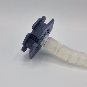 May include: A grey plastic medical device featuring a ridged, flexible tube extending from a square connector. The connector has rectangular tabs and circular openings. The tube is translucent and white.