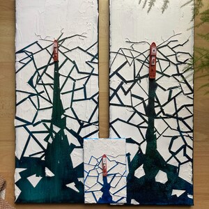 Peut inclure: Deux toiles blanches avec un motif géométrique noir et bleu foncé. Un petit bateau rouge est placé sur chaque toile. Les toiles sont placées sur une surface en bois.
