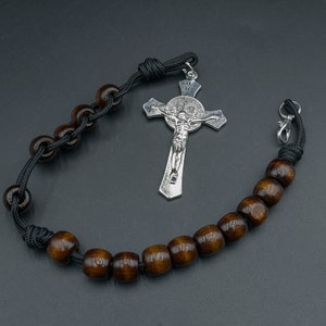 May include: A black cord rosary with brown wooden beads and a silver crucifix featuring a figure of Jesus Christ.