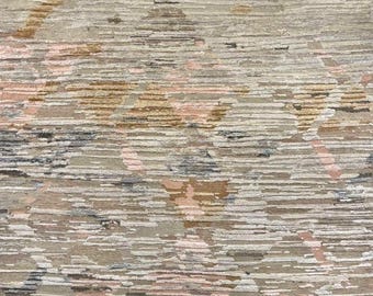 Op de afbeelding: Een getextureerd vloerkleed met een neutraal kleurenpalet. Het vloerkleed heeft een patroon van horizontale lijnen in tinten beige, grijs, roze en bruin. Het ontwerp heeft een abstracte, geometrische uitstraling, geschikt voor interieurdecoratie.