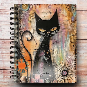 May include: A black cat with yellow eyes and a curled tail is featured on a spiral bound notebook. The background is a collage of colorful patterns and textures. The notebook cover has the name "Sara" written in cursive.
