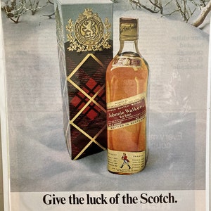 May include: A bottle of Johnnie Walker Red Label Scotch whisky with a red and white tartan box. The bottle is sitting on a snowy surface. The text on the bottle reads "Imported by Somerset Importers, Ltd., New York, N.Y. Blended Scotch Whisky, 86.8 Proof. Johnnie Walker Red Label. Bottled in Scotland."