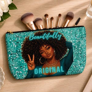 May include: A teal cosmetic bag with a glittery texture, featuring an illustration of a woman with curly hair and the words "Beautifully Original." The bag is open, holding several makeup brushes.