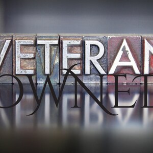 Peut inclure: Les mots "Veteran Owned" sont &eacute;pell&eacute;s en lettres m&eacute;talliques en relief, avec un reflet des lettres sur une surface brillante en dessous.