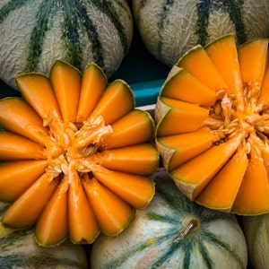 Peut inclure: Gros plan sur une past&egrave;que cantaloup tranch&eacute;e avec une peau verte. La past&egrave;que est dispos&eacute;e en cercle, la chair orange tourn&eacute;e vers l'ext&eacute;rieur. La past&egrave;que est entour&eacute;e d'autres past&egrave;ques cantaloup.