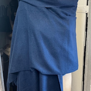 May include: A dark blue shawl with fringe on the bottom edge. The shawl is draped over a mannequin.