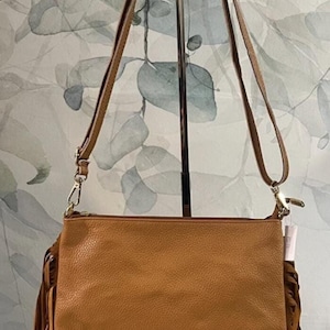 May include: A brown leather crossbody bag with fringe detailing. The bag has a long adjustable strap and a flap closure.