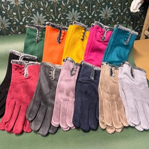 Könnte beinhalten: Eine Sammlung farbenfroher Handschuhe in verschiedenen Farbtönen, darunter Grün, Orange, Gelb und Pink. Jeder Handschuh hat einen Kunstfellbesatz und Knopfdetails. Weitere Farben sind Rot, Grau, Lila, Marineblau, Beige und Hellgrau.