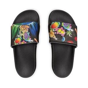 May include: Black slide sandals with a colorful graphic design. The design features a variety of fruits, planets, and other cosmic elements. The sandals have a textured footbed and a white border.